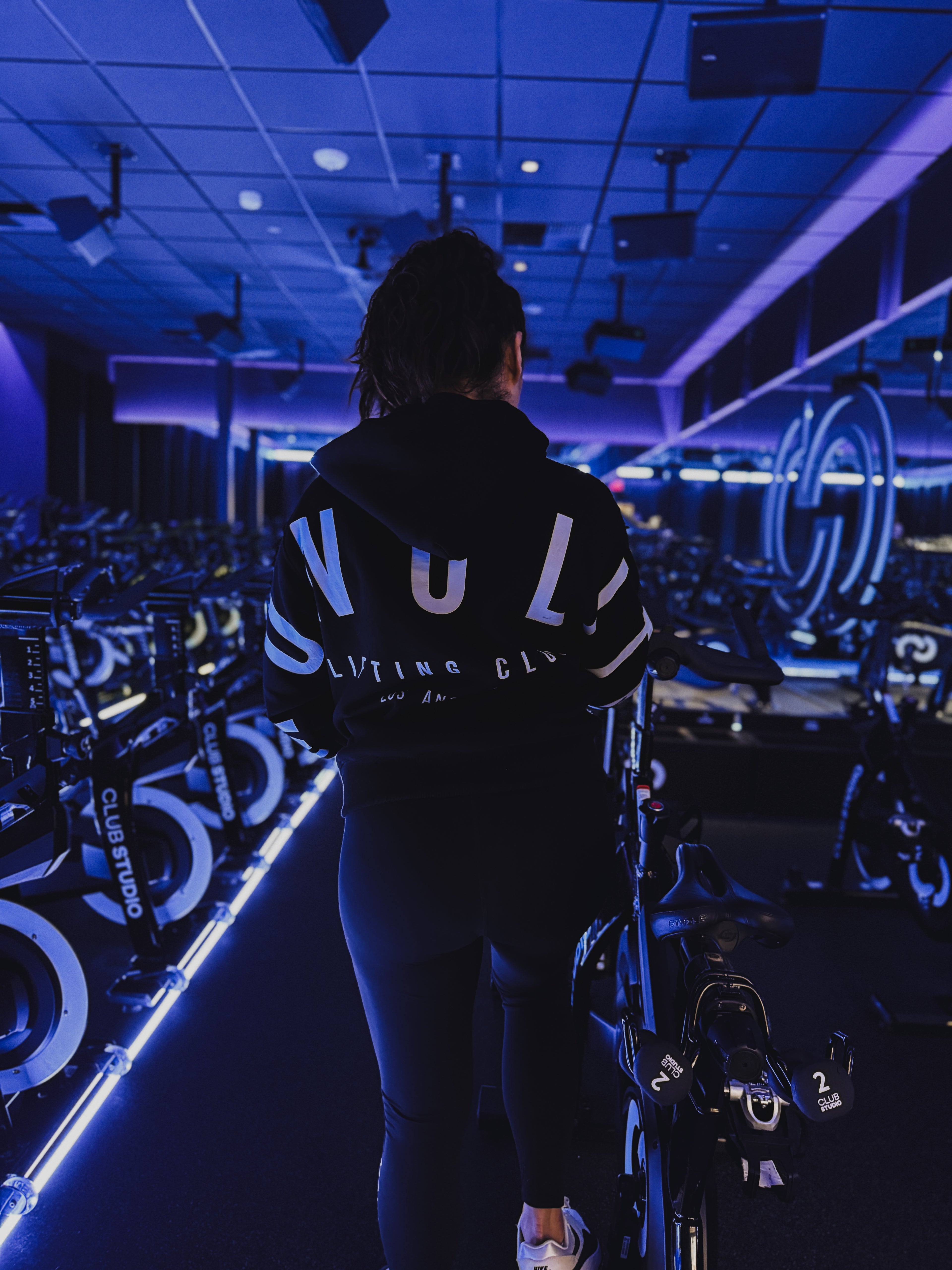 Person wearing a black hoodie with white text in a gym setting