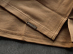 Close-up of a brown fabric with a brand label on a dark surface