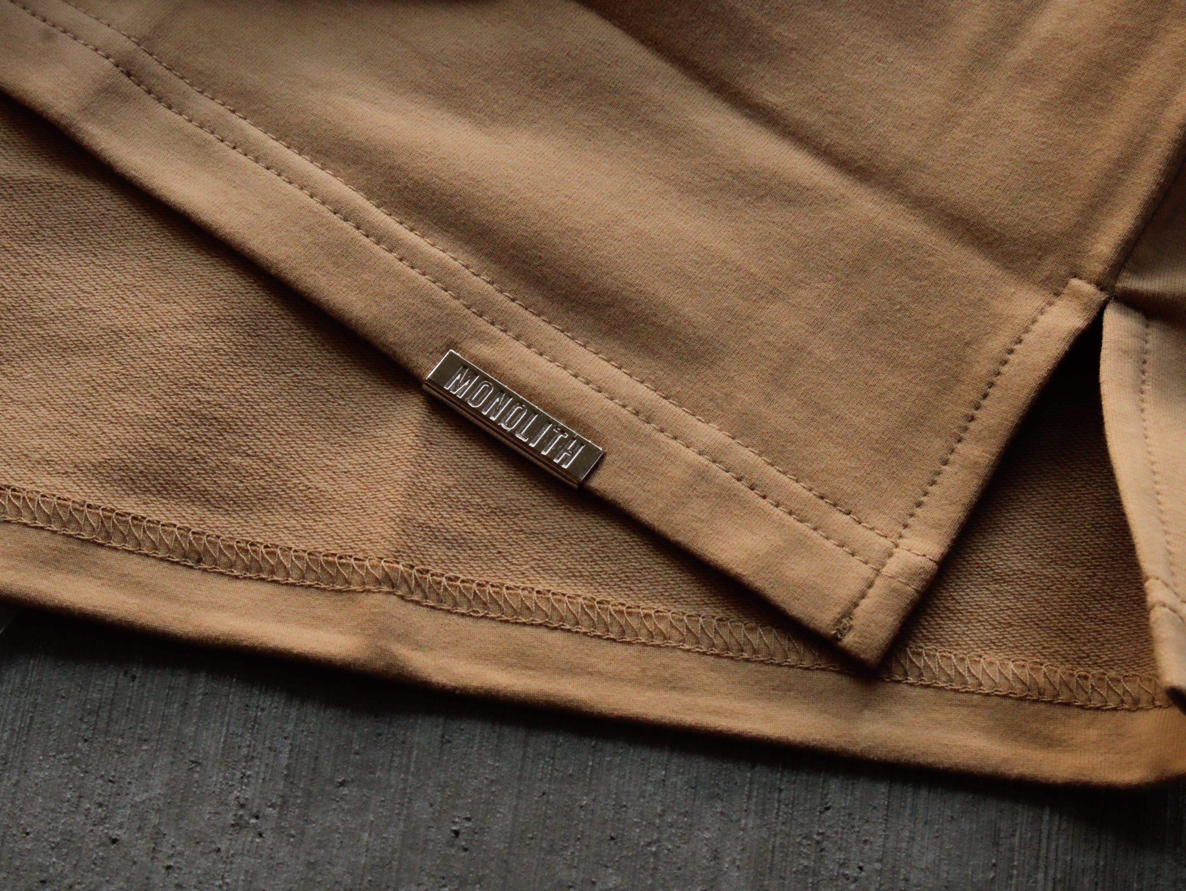 Close-up of a brown fabric with a brand label on a dark surface