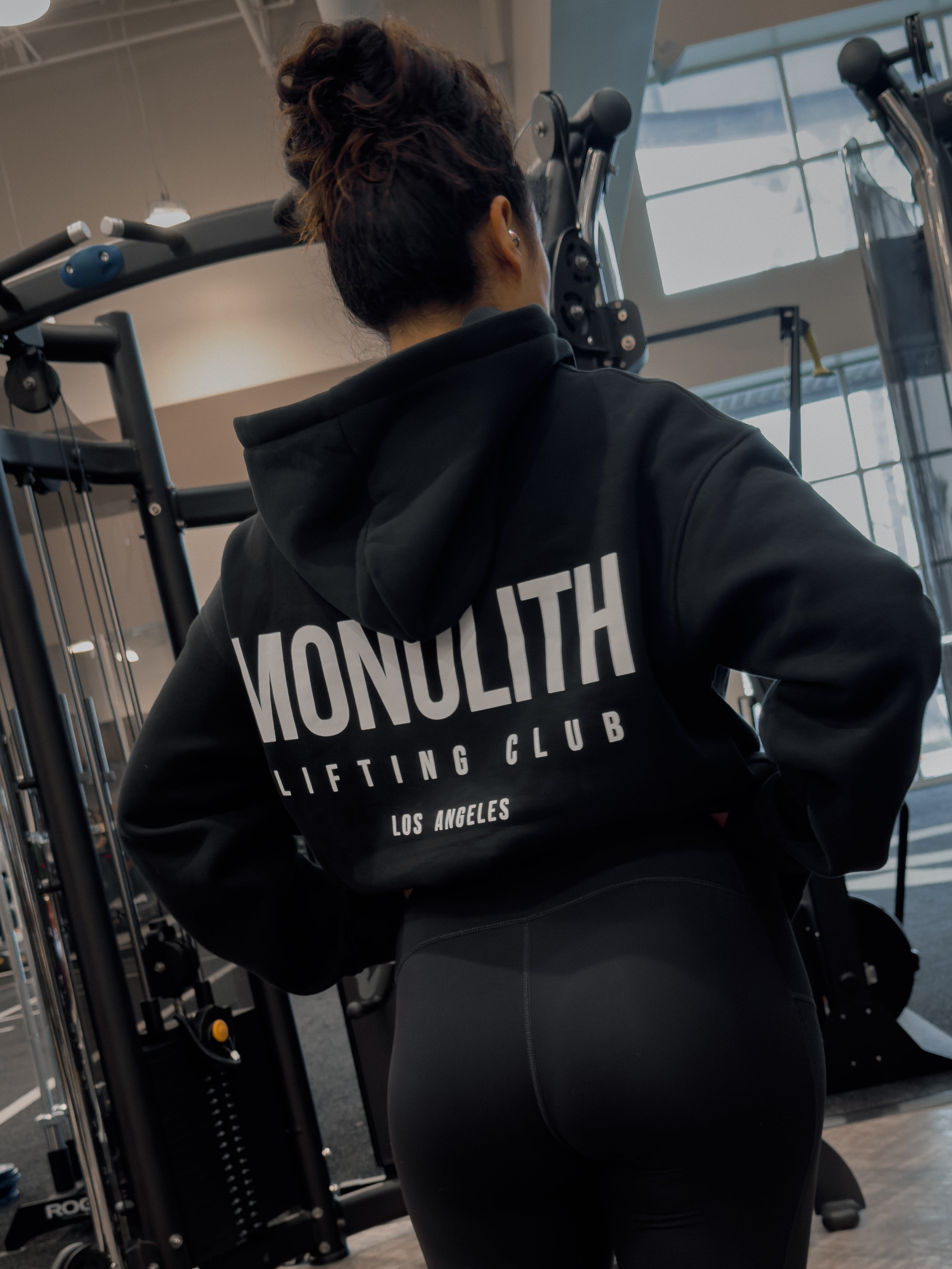 Person wearing a black hoodie with 'Monolith Lifting Club' text in a gym setting