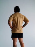 Person wearing a beige t-shirt and black shorts against a light gray background